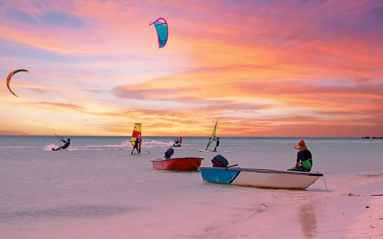Kitesurfistas y windsurfistas en el mar de Aruba al atardecer