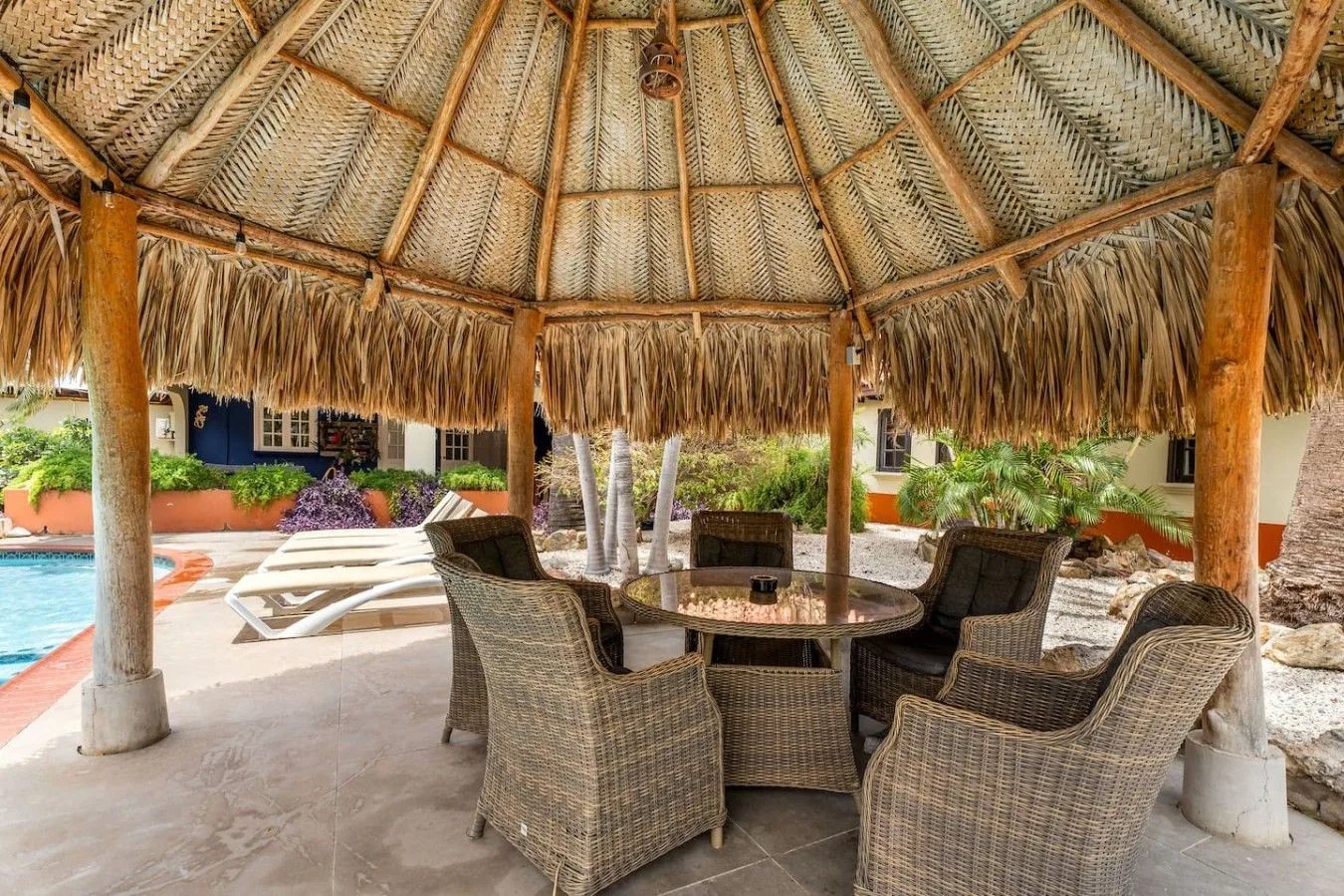 Palapa junto a la piscina con mesa y sillones